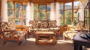 Um quarto aconchegante com móveis de madeira, grandes janelas e vista para uma área arborizada.