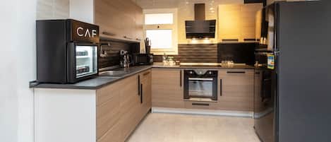 Una cocina moderna con horno empotrado, microondas y cafetera.