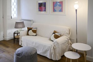 Una sala de estar acogedora con un sofá, una lámpara y dos mesitas.