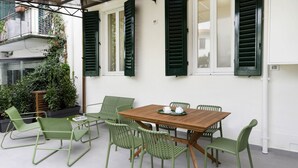 A patio with a wooden table and green chairs, surrounded by white walls and green shutters. - Hidden Gem with Private Garden (Firenze)