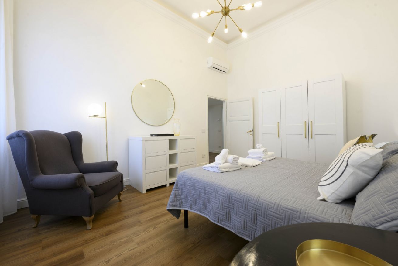 Una camera da letto con un letto, una sedia, un armadio e uno specchio.