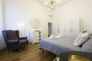 A bedroom with a bed, a chair, a wardrobe, and a mirror.