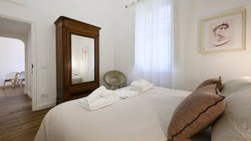 Un dormitorio con una cama grande, un armario de madera, una silla y un cuadro en la pared.