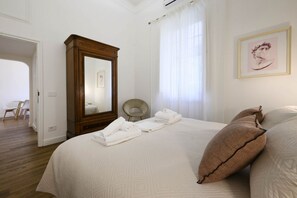 Un dormitorio con una cama grande, un armario de madera, una silla y un cuadro en la pared.