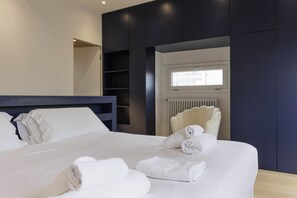 Una habitación de hotel moderna con una cama grande, un armario empotrado, una ventana con persianas y un radiador.