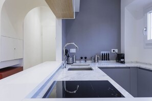A modern kitchen with a black stovetop, white countertops, and a grey backsplash. - Duomo View Apartment (Firenze)