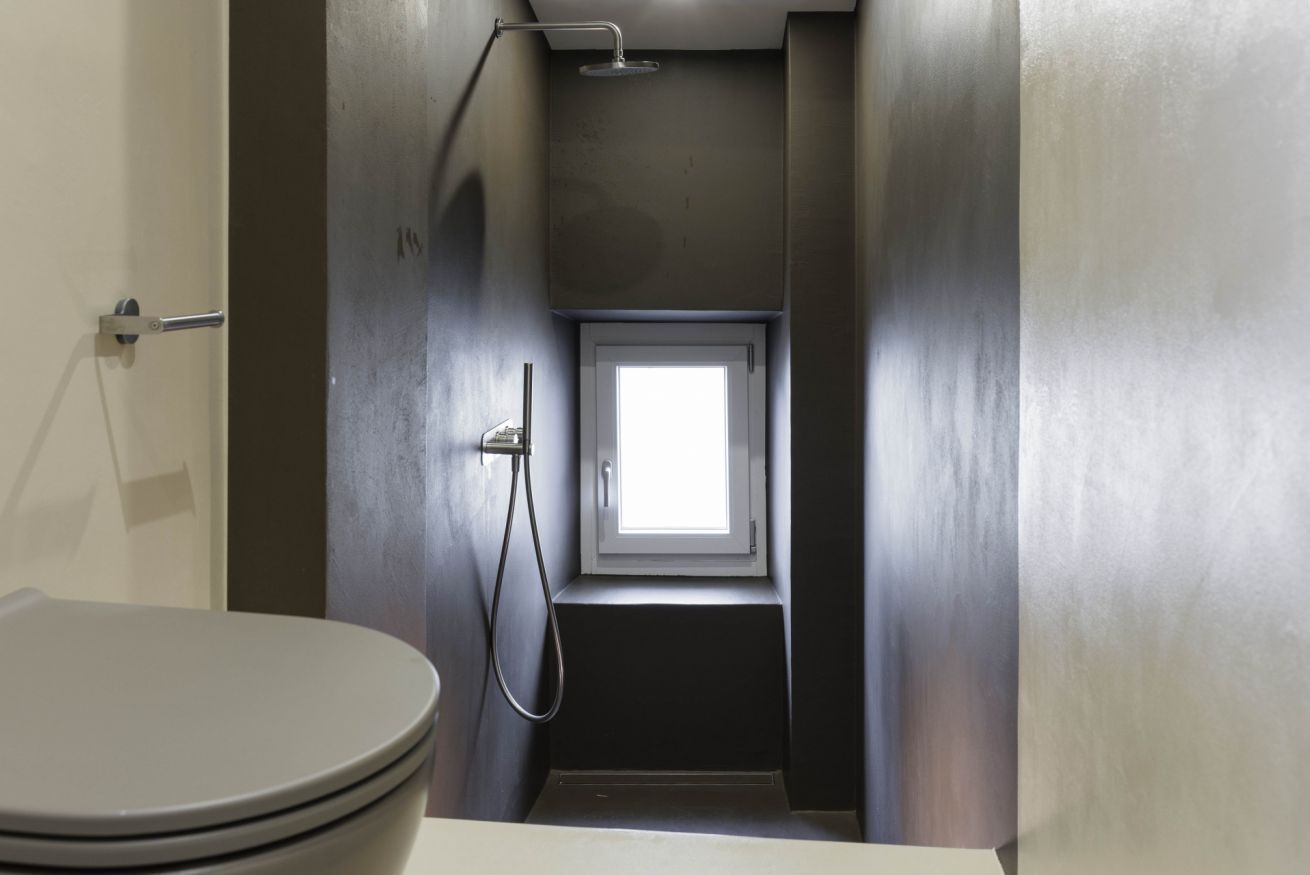 Une petite salle de bain comprenant des toilettes, une douche et une petite fenêtre.