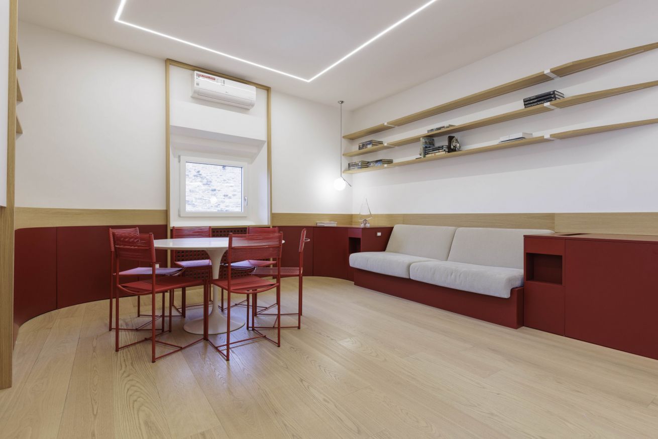 A modern room with a dining area, a sofa, and built-in shelves.
