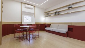 A modern room with a dining area, a sofa, and built-in shelves.