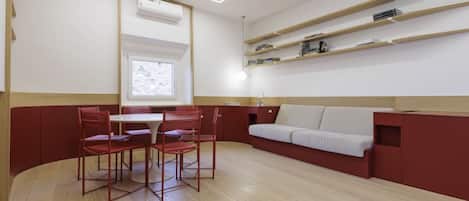 A modern room with a dining area, a sofa, and built-in shelves.