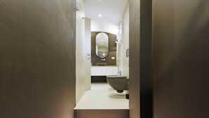 A modern bathroom with a large oval mirror, a vessel sink, and a toilet.