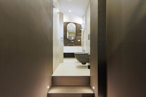 Un baño moderno con un espejo ovalado grande, un lavabo sobre encimera y un inodoro.
