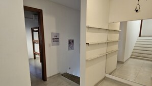 A spacious hallway with tiled floors, white walls, and a staircase leading to another level. There are several empty shelves along the walls and a door leading to another room. - Búzios Geribá beach house (Búzio)