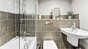 Ein modernes Badezimmer mit einer Glaskabine zur Dusche, einem freistehenden Waschbecken und einer Toilette.