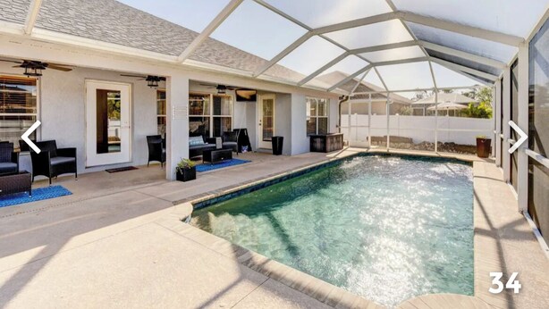 A covered outdoor swimming pool with a patio area, including seating and a door leading to the house. - Pool Home in SW Florida. 4 bedrooms,2 bathrooms, close to shopping and beaches. (North Port)