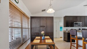 A modern kitchen with dark wooden cabinets, a built-in microwave, and a dining area with a wooden table and chairs. - Pool Home in SW Florida. 4 bedrooms,2 bathrooms, close to shopping and beaches. (North Port)
