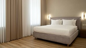Ein modernes Hotelzimmer mit einem großen Bett, hellen Vorhängen und Holzboden.