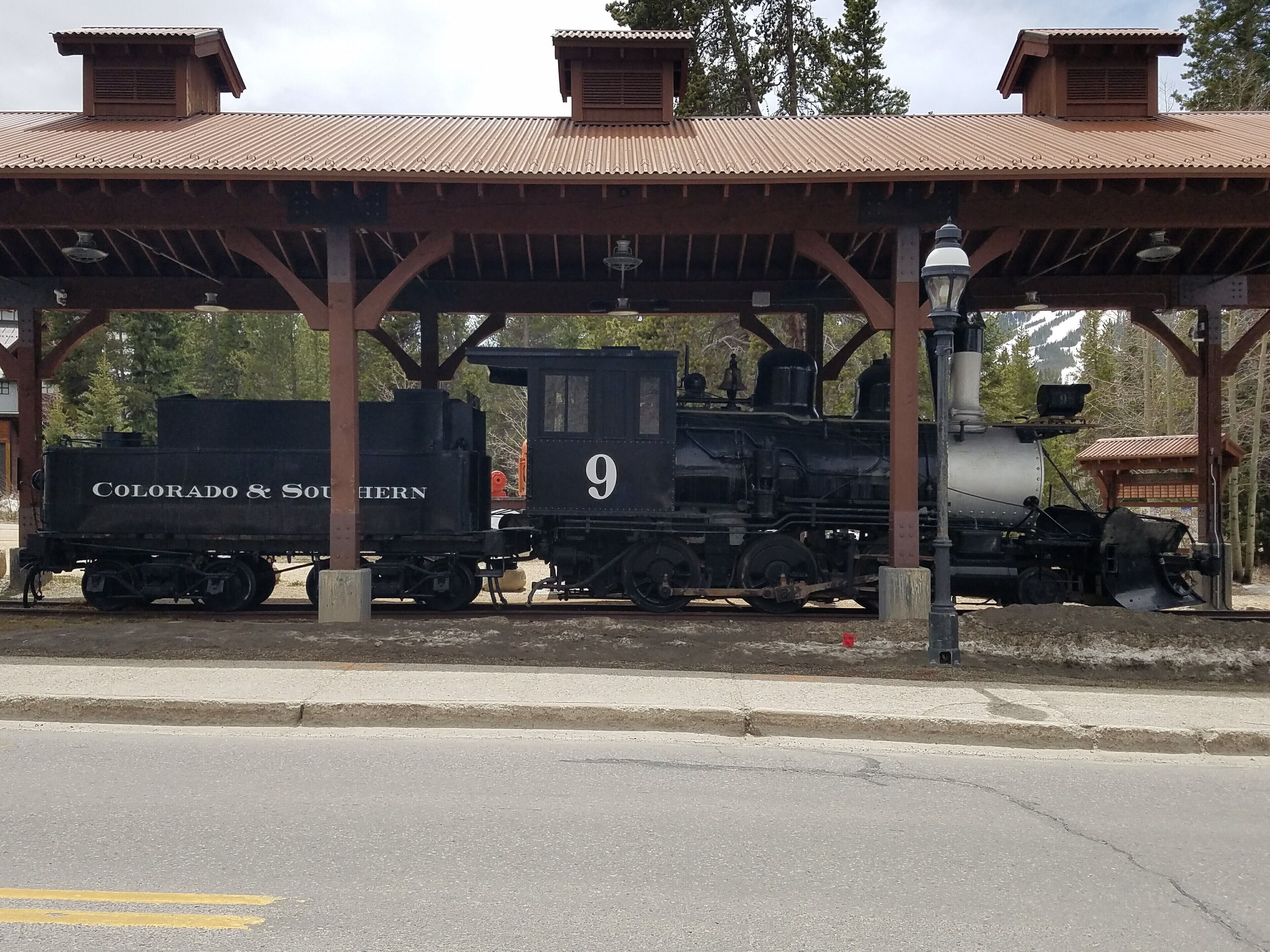 A train station with a covered platform and a vintage train labeled "Colorado & Southern" number 9.