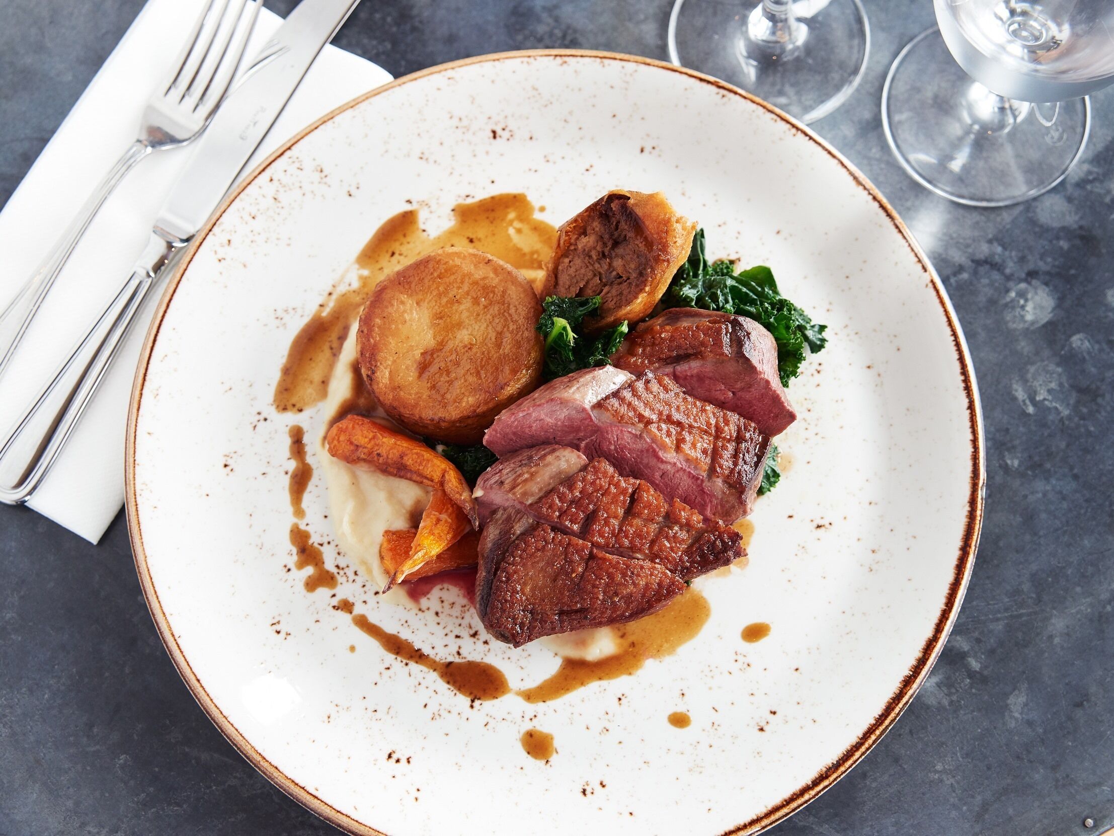 A plate of food with steak, roasted potatoes, and greens.