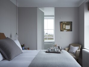 A neatly arranged bedroom with a bed, a chair, a tray with cups and a vase, and a window with a view. - The House at Ramsgate (Ramsgate)