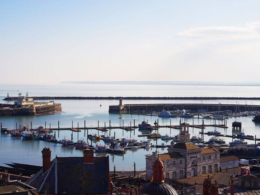 Un puerto con barcos, un faro y un edificio con cúpula.