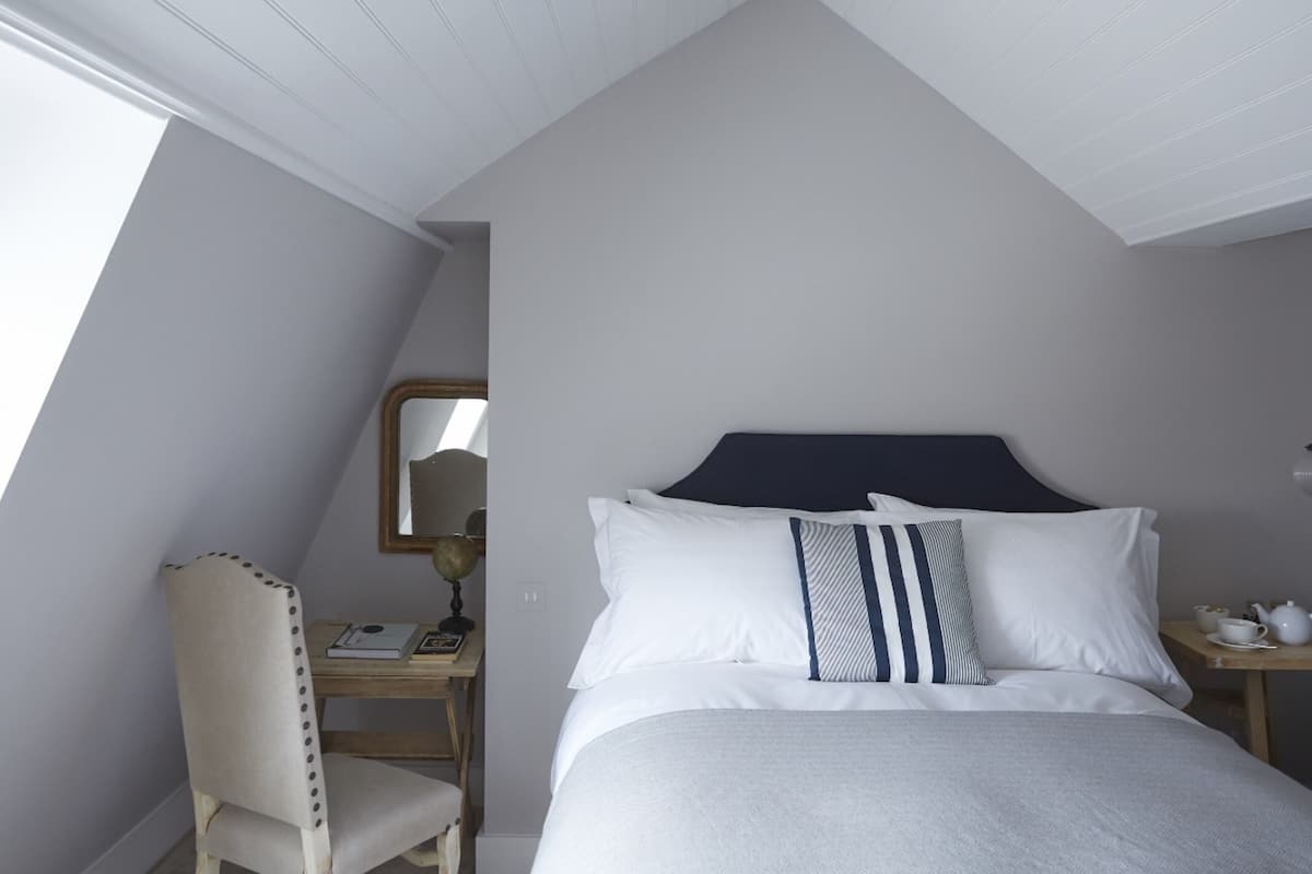 A bedroom with a bed, a desk, a chair, and a nightstand.