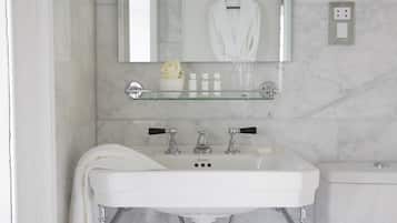 A bathroom with a white sink, a mirror, and a glass shelf above the sink.