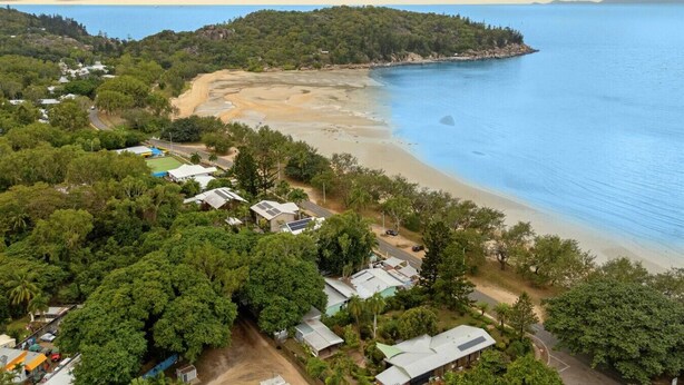 An aerial view of a coastal area with a beach, houses, and dense greenery. - Welcome to The Island House (Arcadia)