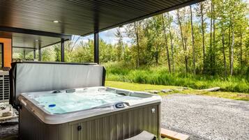 A hot tub outdoors with a view of a forest.