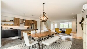 Une cuisine moderne dotée d’un îlot central, de meubles en bois et de luminaires suspendus.