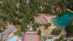 Vista aérea de una zona residencial con piscina, canchas de tenis y playa.