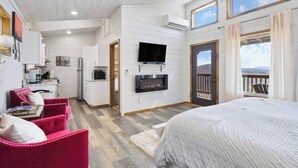 A cozy bedroom with a large bed, a TV mounted on the wall, and a balcony with a view. - Modern Retreat, King Suite, River Views (Carroll County)