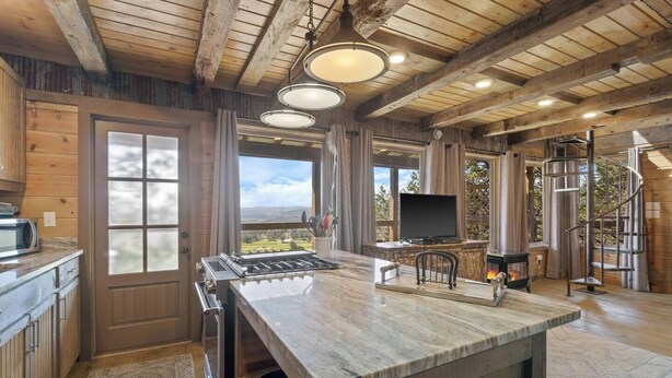 Una cocina espaciosa con una isla grande, vigas de madera y vistas al exterior.