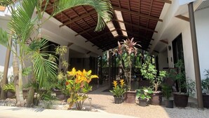 A covered outdoor area with a wooden roof, surrounded by various potted plants and palm trees. - Beautiful complex with swimming pool, close to the beach and downtown. (Sámara)