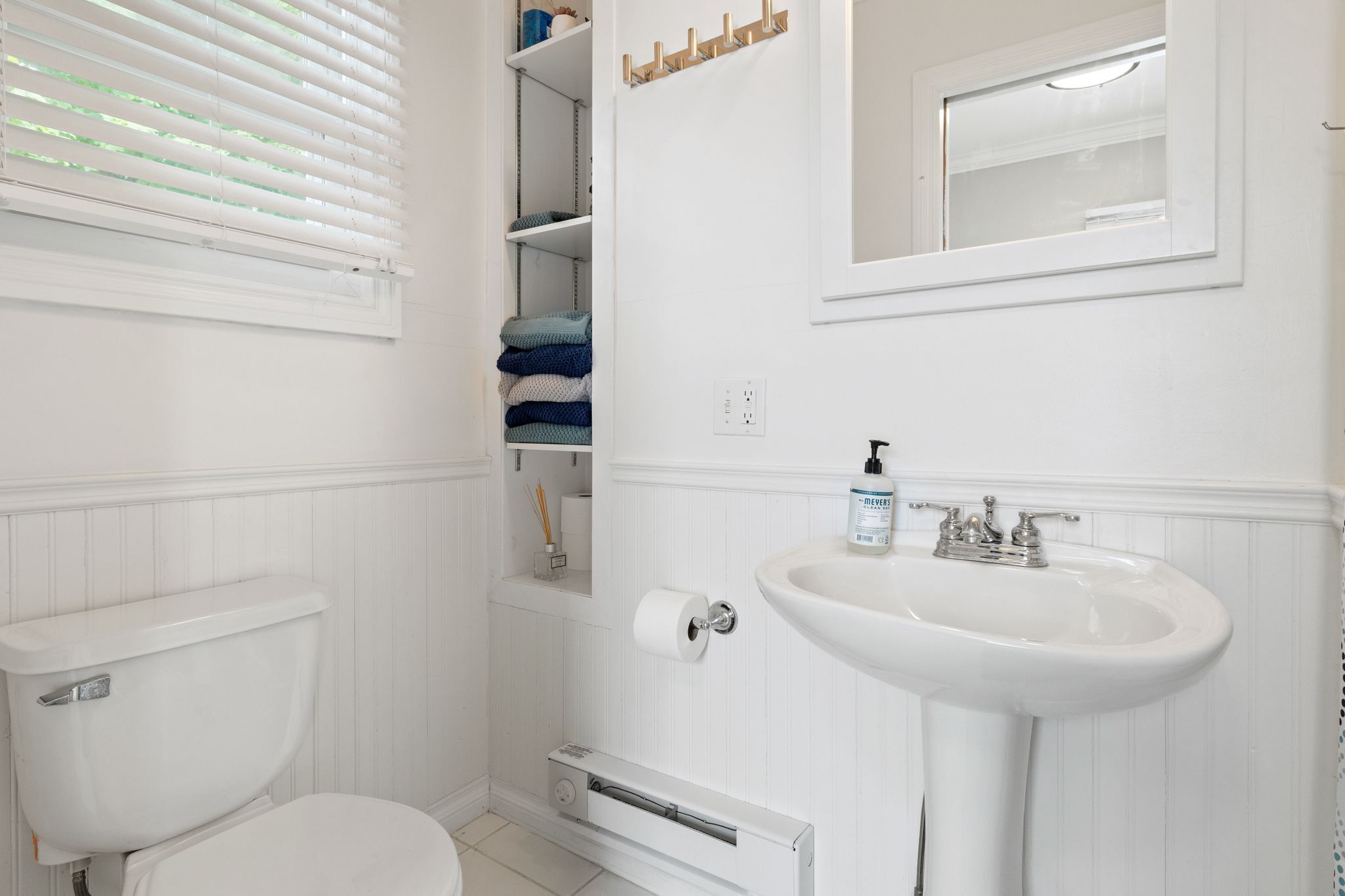 Een badkamer met toilet, wastafel, spiegel en handdoekhouder.