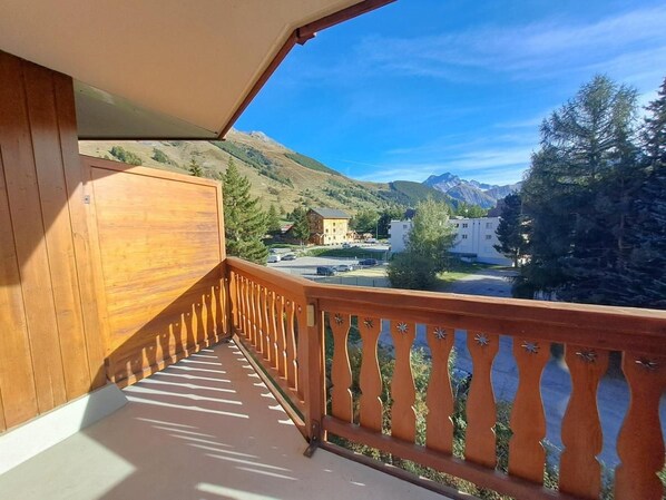 A balcony with a wooden railing overlooking a mountainous landscape.