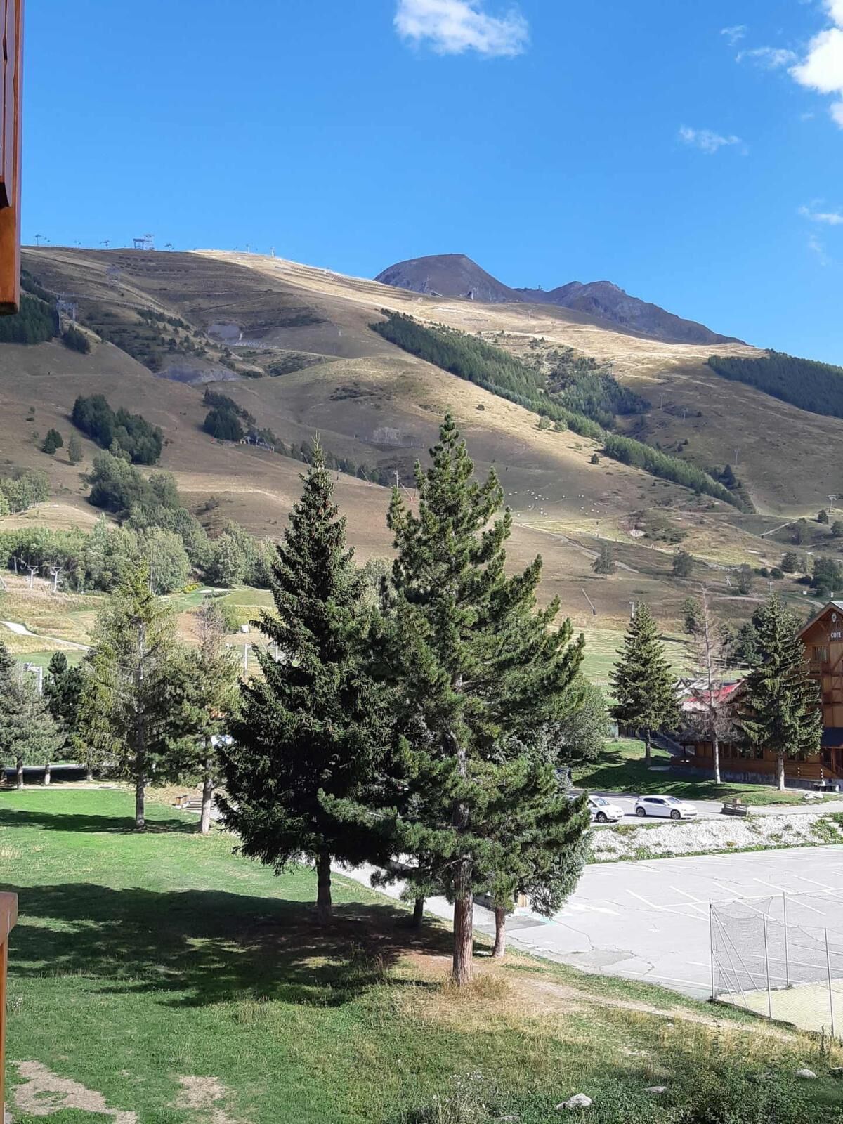 A mountainous landscape with a clear sky. There are trees and a building with a sign that reads "Café".