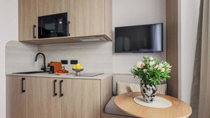 Cocina compacta con microondas, pileta y televisor de pantalla plana montado en la pared.