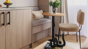 Una sala de estar moderna con un sofá, una mesa de centro con un libro, una mesita con un jarrón y una silla.