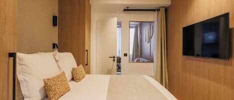 Ein Hotelzimmer mit einem großen Bett, einem an der Wand befestigten Flachbildfernseher und einer Tür zu einem Badezimmer.