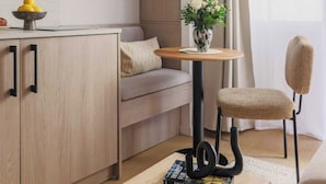 Una sala de estar moderna con un sofá, una mesa de centro con un libro, una silla y una mesita con un jarrón de flores.