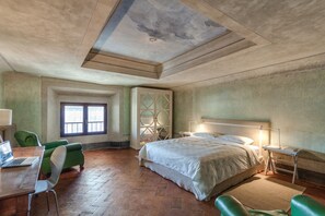 A bedroom with a large bed, a desk with a laptop, green chairs, a window, and a decorative ceiling. - Accademia Frescoes Apartment (Firenze)