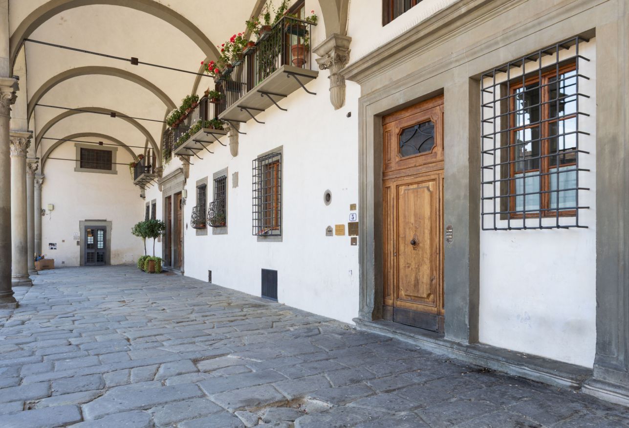 Una stretta strada acciottolata fiancheggiata da edifici bianchi con portali e finestre ad arco.