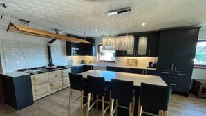 Una cocina moderna con una isla central, armarios negros y techo de madera.