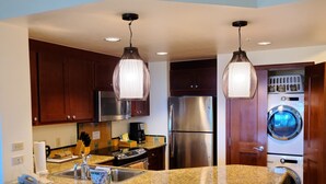 A modern kitchen with granite countertops, stainless steel appliances, and pendant lighting.