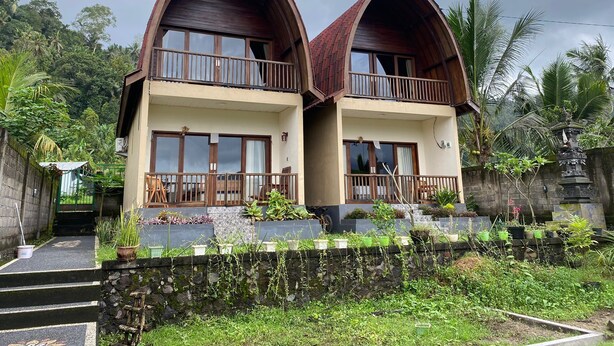 A two-story building with a steeply pitched roof and wooden balconies. - Villa Anteng (Sidemen)