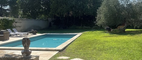 Un patio trasero con piscina, escalones de piedra y césped.