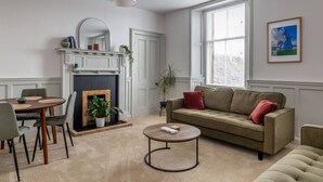Una sala de estar con chimenea, un sofá, una mesa de centro y un comedor con sillas.