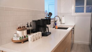 Een moderne keuken met een koffiezetapparaat, mokken en een waterfles.