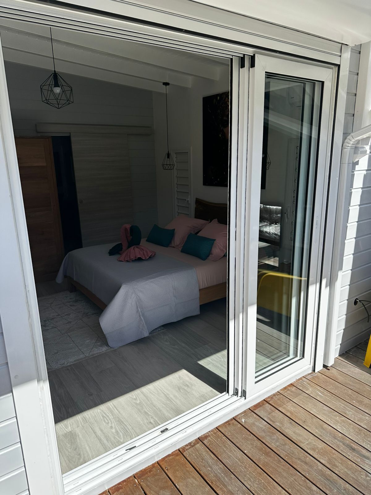 A bedroom with a bed, pillows, and a sliding glass door leading to a balcony.